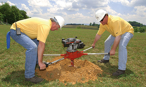 2 Men drilling the ground to install an direct buried pole